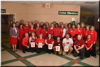 This is a picture of some of the staff of the hospital all wearing red holding a sign that says GO RED